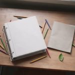 Planificación docente, cuaderno y lápices de colores sobre un escritorio
