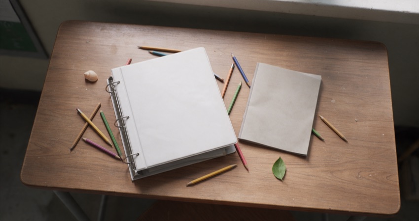 Planificación docente, cuaderno y lápices de colores sobre un escritorio